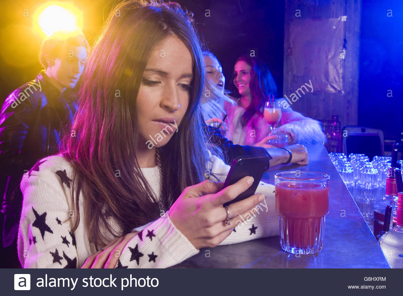 pensive-young-woman-texting-on-cell-phone-in-nightclub-G8HXRM.jpg
